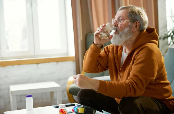 Starszy Mężczyzna Laską Siedzący Obok Stołu Lekami Smartfonem Szklanką Wody — Zdjęcie stockowe