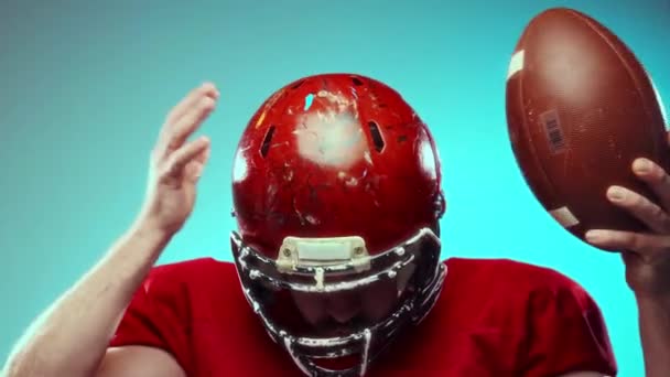 エネルギーをゲームに投入する ヘルメット ユニフォーム ボールの感情的なアメリカンフットボールプレーヤーは 激しい感情を表現し 青い背景に叫びます プロスポーツ コンテスト トーナメント — ストック動画