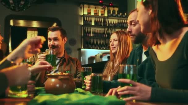 陽気な若者たち パブで会う友人たち グリーンビールのメガネを飲みながら 話したり 笑ったり トーストを言ったりする 聖パトリックデーのお祝い レジャー時間 楽しみ 伝統の概念 — ストック動画