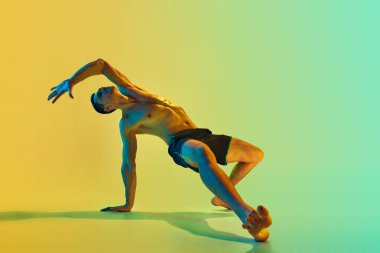 Yoğun bir vücut eğitimi. Kaslı, atletik, formda vücudu olmayan, neonlu sarı arka plana karşı egzersiz yapan genç bir adam. Aktif ve sağlıklı yaşam tarzı, spor anlayışı