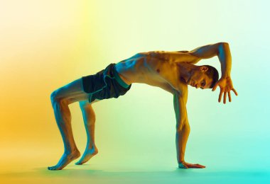 Yoğun bir vücut eğitimi. Kaslı, atletik, formda vücudu olmayan, neonlu sarı arka plana karşı egzersiz yapan genç bir adam. Aktif ve sağlıklı yaşam tarzı, spor anlayışı