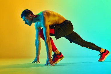 Koşmaya hazırız. Kaslı, sportif genç adam, neon ışıkta mavi renkli arka plana karşı üstsüz antrenman yapıyor. Aktif ve sağlıklı yaşam tarzı kavramı, spor, fitness, dayanıklılık