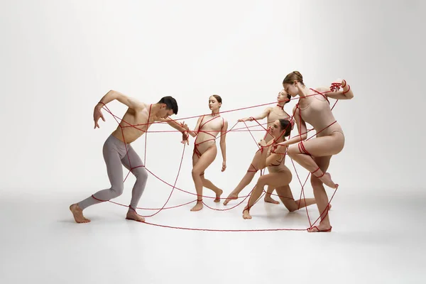 Půvabní Baletní Tanečníci Vystupující Červeným Provázkem Spojeným Mladým Mužem Bílém — Stock fotografie