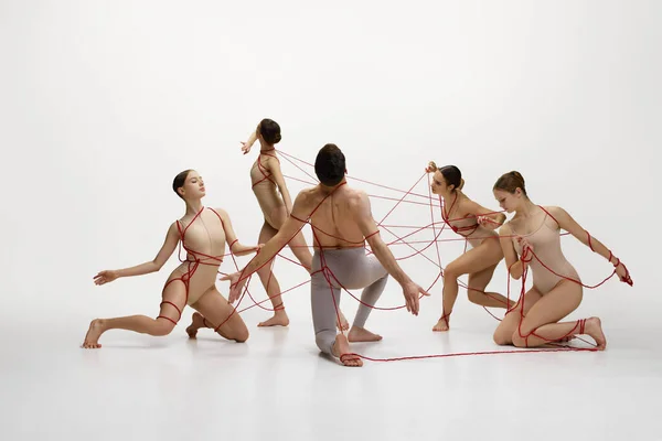 社会的なつながりと自由 バレエダンサーは赤い弦で繋がり 白いスタジオのバックグラウンドで演奏する 古典舞踊コンセプト モダンスタイル インスピレーション — ストック写真