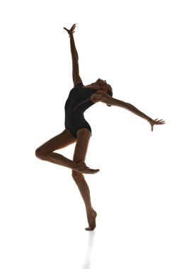 Yetenekli, sanatsal bir genç kızın tam boy görüntüsü sahne kostümlü ritmik jimnastikçi beyaz stüdyo arka planına karşı gösteri yapıyor. Spor, güzellik ve zarafet kavramı, rekabet, sanat, gençlik, hobi