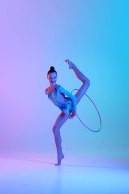 Dinamik, uzun metrajlı bir genç kız, ritmik jimnastikçi halkayla neon ışıklarındaki gradyan stüdyo arka planına karşı gösteri yapıyor. Spor, güzellik ve zarafet kavramı, rekabet, sanat, gençlik, hobi