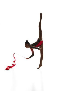 Tel. Hareketli kadın ritmik jimnastikçi, beyaz stüdyo arka planında kurdeleli genç kız sahne alıyor. Spor, güzellik ve zarafet kavramı, rekabet, sanat, gençlik, hobi