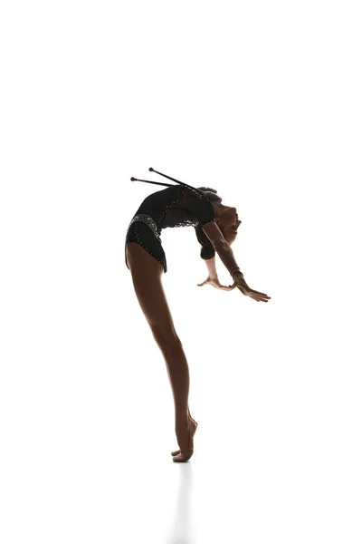 优雅的动作 年轻美丽的女孩 身穿黑色舞台服装的有节奏的体操运动员 在白人工作室的背景下表演 美的概念 — 图库照片
