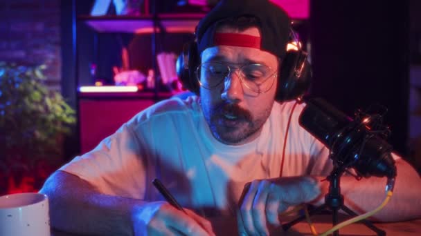 Gözlüklü Şapkalı Bir Adam Neon Işıklarla Evde Oturuyor Çevrimiçi Video — Stok video