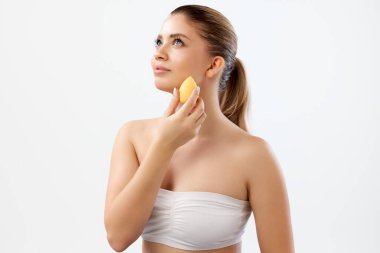 Güzel genç bir kadın, beyaz stüdyo arka planına vakıf kurmak için güzellik blenderi kullanıyor. Çıplak makyaj. Güzellik, cilt bakımı, kozmetik ve kozmetik kavramı