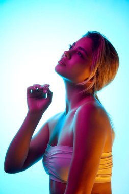 Sağlık ve kendine bakıcılık. Stüdyonun arka planında neon ışığı altında sakin bir yüz ifadesi olan güzel bir genç kız. Güzellik, cilt bakımı, kozmetik ve kozmetik kavramı