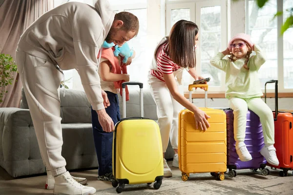家族は 自宅のリビングルームで荷物を持ってバッグを閉じながら冒険の準備をします 休日と休暇を一緒に 旅行代理店 リラックスの概念 アドベンチャー — ストック写真
