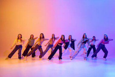 Genç kızların eğitimlerinin dinamik görüntüsü. Dans eden hip hop, modern dans stili, neon ışıkta, gradient stüdyo arka planına karşı. Hobi kavramı, gençlik, çocukluk, tarz, moda, dans okulu