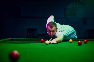 Vuruş yapan bir oyuncunun dinamik çekimi, bilardo şampiyonası ve yerel turnuvalar için enerji ve heyecan ifade ediyor. Snooker oyunu. Bilardo, spor, kumar, hobi, eğlence kavramı.