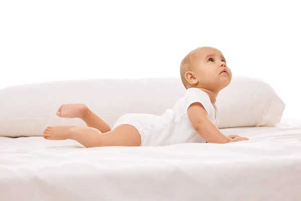 遊び心のある アクティブなスマートな子供 ベッドの上に横たわる小さな赤ん坊の少女は 白い背景に対する好奇心と注意を示しています 幼少期 幼児期 ヒースの概念 — ストック写真