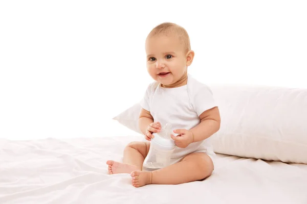 小さい赤ん坊の子供 白い子供の可愛い赤ん坊は枕でベッドに座って白い背景に対して微笑んでいます 幼少期 幼児期 ヒースの概念 — ストック写真