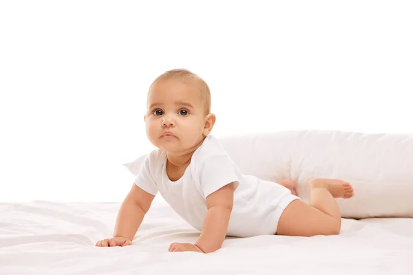 美しい赤ちゃん 白い快適な服の小さな女の子は 白い背景の背後にある枕でベッドの上に横たわっています 幼少期 幼児期 ヒースの概念 — ストック写真