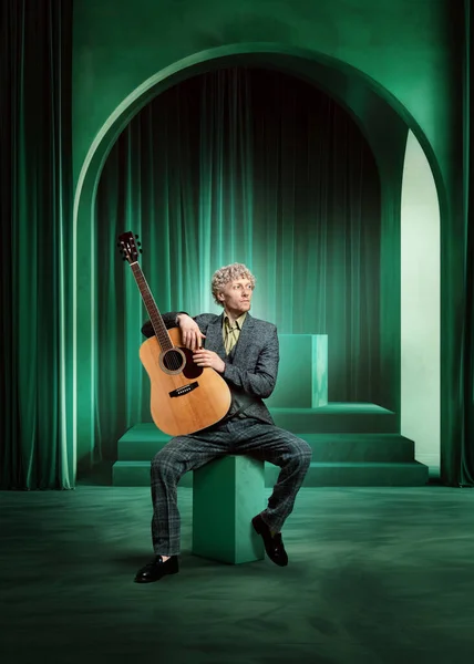 Человек Костюме Спокойным Выражением Лица Музыкант Сидящий Гитарой Зеленой Роскошной — стоковое фото