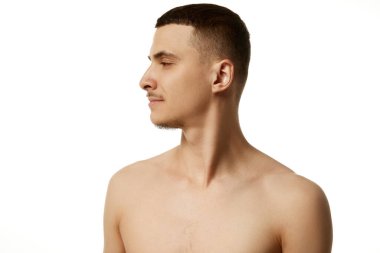 Beyaz stüdyo geçmişine karşı çıplak omuzlu esmer ve sakallı bir adamın profil görüntüsü. Güzel insanlar. Güzellik prosedürleri, erkek sağlığı, vücut bakımı, kaplıca tedavisi, hijyen.