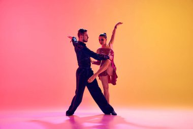 Tutkulu dansçılar. Sanatçı, yetenekli genç adam ve kadın, güzel sahne kostümleriyle dans ediyorlar. Neon ışıkta, değişken pembe arka plana karşı dans ediyorlar. Dans sınıfı kavramı, sanat.