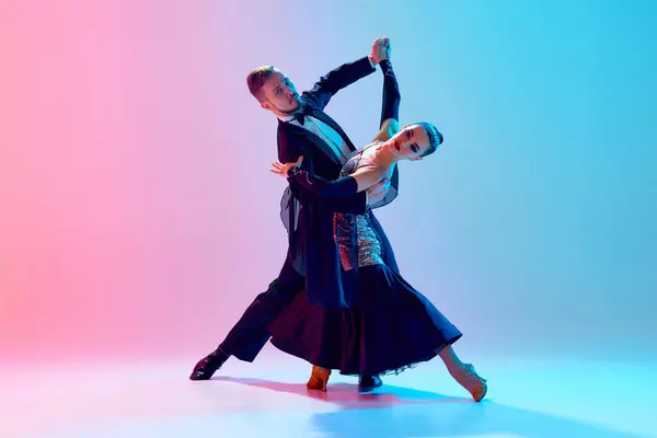 エレガントで情熱的な若いカップル 男性と女性は ネオンライトのグラデーションピンクブルーの背景に対してバックステージでボールルームを踊ります ダンスクラスのコンセプト ダンススクール — ストック写真