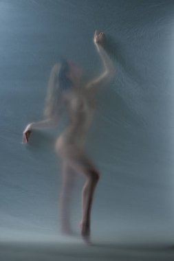 Şeffaf mat camına çıplak poz veren ince, çıplak vücutlu zarif genç bir kadının silueti. Özgürlük ve kişisel bakım. Vücut estetiği kavramı, kadınlık, güzellik, sağlık, sanat