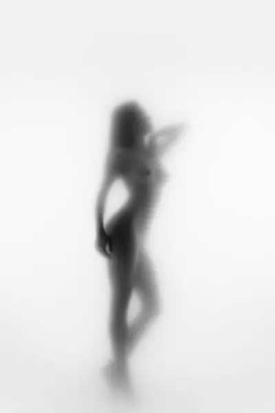 Monochrome abstract female silhouette, young woman with slim, fit body posing naked against blurred background. Self-acceptance. Concept of body aesthetics, femininity, beauty, health, art