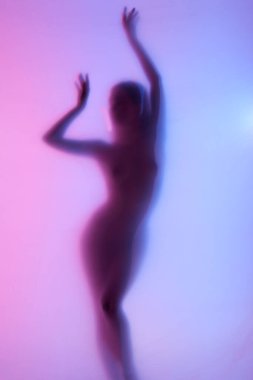 Sıska, formda, neon rengi arka planda çıplak poz veren zarif bir kadının bulanık silüeti. Özgürlük ve kendini sevme. Vücut estetiği kavramı, kadınlık, güzellik, sağlık, sanat