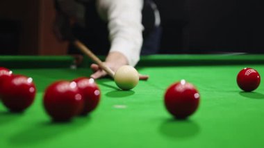 Beyaz gömlekli yakışıklı genç adam bilardo oynuyor, bilardo oynuyor, ıstakayla atış yapmaya odaklanıyor. Konsantre oyuncu. Toplara odaklan. Bilardo, spor, kumar, hobi, eğlence, oyun kavramı