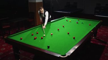 Odaklanmış genç adam vuruşunu bilardo masasında yapıyor, hassasiyet ve beceri gösteriyor. Yerel bilardo turnuvasının tanıtımı. Bilardo, spor, kumar, hobi, eğlence, oyun kavramı