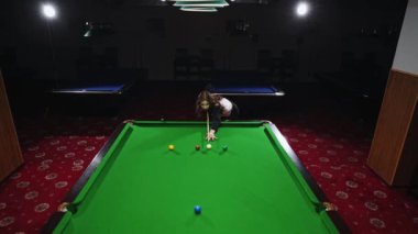 Bilardo oynayan bir kadın yeşil masadaki bilardo toplarını hedef alıyor. Snooker maçı, turnuva. Hareketli odak. Bilardo, spor, kumar, hobi, eğlence, oyun kavramı