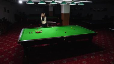 Bilardo oynayan bir kadın yeşil masadaki bilardo toplarını hedef alıyor. Snooker maçı, turnuva. Hareketli odak. Bilardo, spor, kumar, hobi, eğlence, oyun kavramı