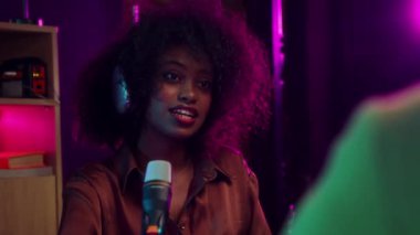 Gülümseyen genç Afrikalı kadın, sosyal medya etkileyicisi, mikrofonlu blog yazarı ve online podcast için röportaj yapıyor. Çevrimiçi iletişim kavramı, modern teknoloji, kitle iletişim