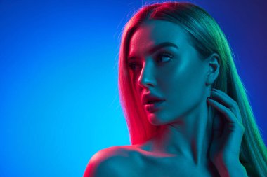 Yirmili yaşlardaki güzel bir kadının portresi. Pürüzsüz, sağlıklı, parlak bir teni ve mavi stüdyo ışıkları altında sarı saçları var. Doğal güzellik kavramı, kozmetik, kozmetik, cilt bakımı