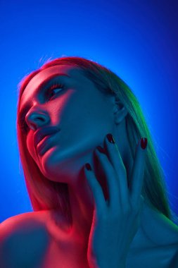 Yüz gerdirme. 20 'li yaşlarda güzel bir kadının portresi. Sarı saçlı, pürüzsüz tenli ve mavi arka planda çıplak omuzlu. Doğal güzellik kavramı, kozmetik, kozmetik, cilt bakımı