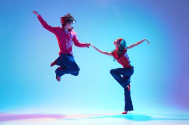 Modaya uygun genç adam ve güzel kadın mavi arka planda rock 'n roll dansı yapıyorlar. Hobi kavramı, dans sınıfı, parti, 50 'ler, 60' lar kültürü, gençlik