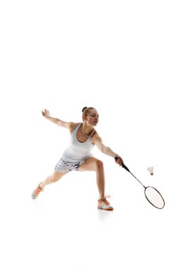 Konsantre genç kız, raketle hareket eden atlet, beyaz arka planda izole edilmiş badminton oynuyor. Antrenman. Profesyonel spor anlayışı, aktif yaşam tarzı, hobi, oyun