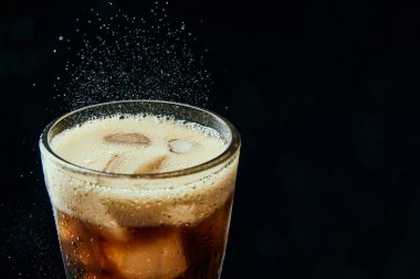 Cam gibi köpüklü içecek, soda, kola, siyah arka planda buzlu koyu bira. Alkol ve alkolsüz içecek kavramı, ferahlatıcı. Poster, reklam afişi