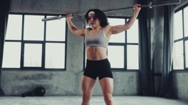 Spor giyimli atletik genç kız spor salonunda halterle çalışıyor. Güç ve güç. Profesyonel spor anlayışı, aktif yaşam tarzı, vücut geliştirme. Reklam. Video, 4k