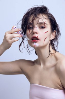 Modern çağda güzelliğin kurbanları. Dudaklarında şırınga ve yüzünde çizikler olan güzel bir genç kadın. Modern güzellik standartları kavramı, plastik cerrahi, sağlık, kozmetoloji