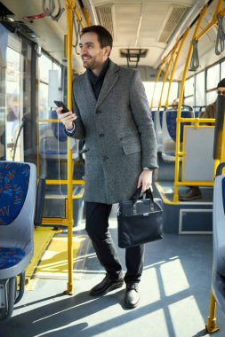 Gri montlu adam modern tramvayda duruyor. Hızlı ve uygun bir ulaşım yolu. Toplu taşıma kavramı, şehir yaşam tarzı, günlük yaşam tarzı