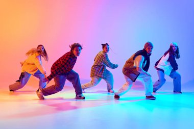 Genç insanlar, dinamik pozlar veren erkekler ve kadınlar hip hop dansı yapıyor, neon ışıklarındaki gradyan stüdyo arkaplanına karşı çağdaş dans. Modern dans tarzı, hobi, aktif yaşam tarzı, gençlik kültürü kavramı