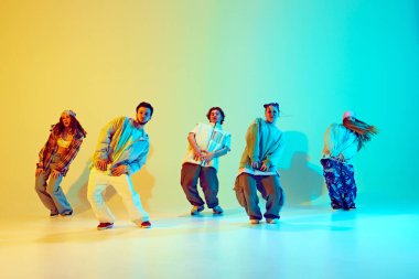 Senkronize hareketler. Bir grup genç, neon ışıkta yeşil arka plan üzerinde kafa yoruyor. Modern dans tarzı, hobi, aktif yaşam tarzı, gençlik kültürü kavramı