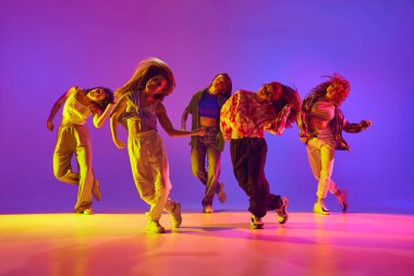 Hareketli gündelik giysiler içindeki genç yetenekli kadınların dinamik görüntüsü, neon rengi arka planda dans eden sokak dansı. Gençlik kavramı, sokak dansı, modern dans, modern dinamik.