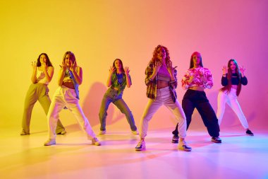 Sanatsal, yetenekli, hareketli genç kadınlar, neon ışıkta arka planda sokak dansı yapıyorlar. Gençlik kavramı, sokak dansı, modern dans, modern dinamik.