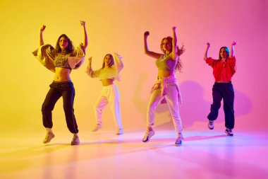 Spor tarzında şık genç kadınlar gündelik kıyafet günah hareketi, dans eden hip hop, neon ışıkta değişen arka plana kafa yormak. Gençlik kavramı, sokak dansı, modern dans, modern dinamik.