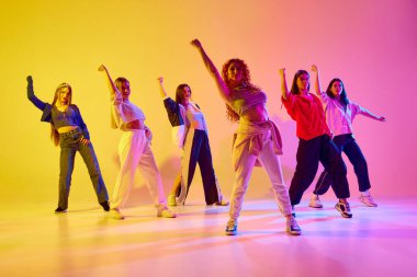 Yetenek gösterisi. Genç kadınlar, bir grup sanatçı kadın dansçı, neonlu arka planda sokak dansı yapan bir kadın. Gençlik kavramı, sokak dansı, modern dans, modern dinamik.