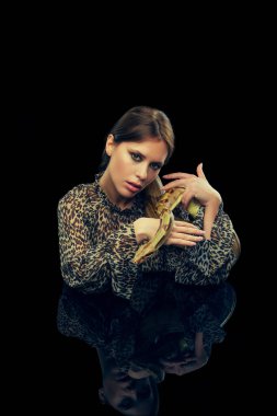 Siyah stüdyo arka planında yılanla poz veren makyajlı genç kadın portresi. Kadın güzelliği kavramı, hayvan teması, özen, zarafet, moda