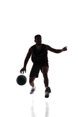 Silhouette of competitive young man, basketball athlete during game, training, dribbling ball isolated on white background. Concept of professional sport, competition, game, tournament, action clipart