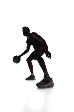 Silhouette of young man, basketball player in motion, training, playing, dribbling ball isolated on white background. Concept of professional sport, competition, game, tournament, action clipart